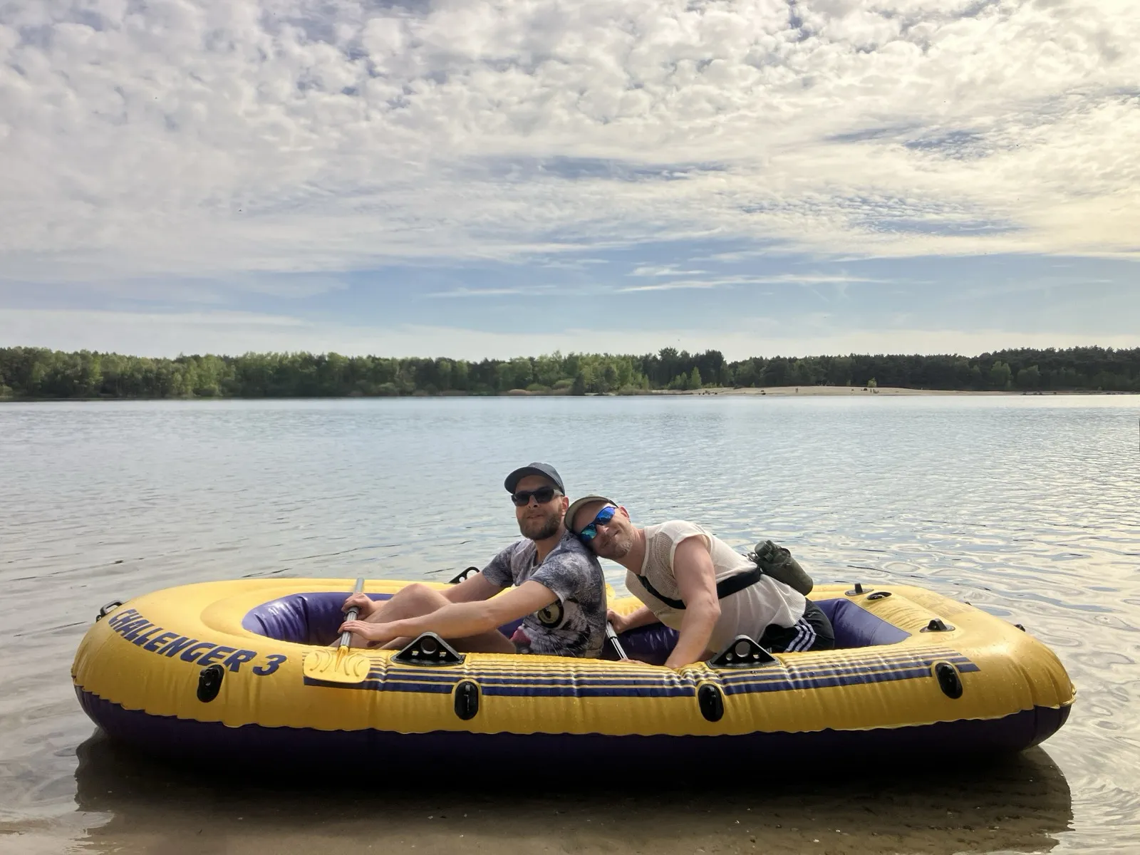 Two faeries side by side in a yellow inflatable dinghy at the water’s edge, grinning at the camera.